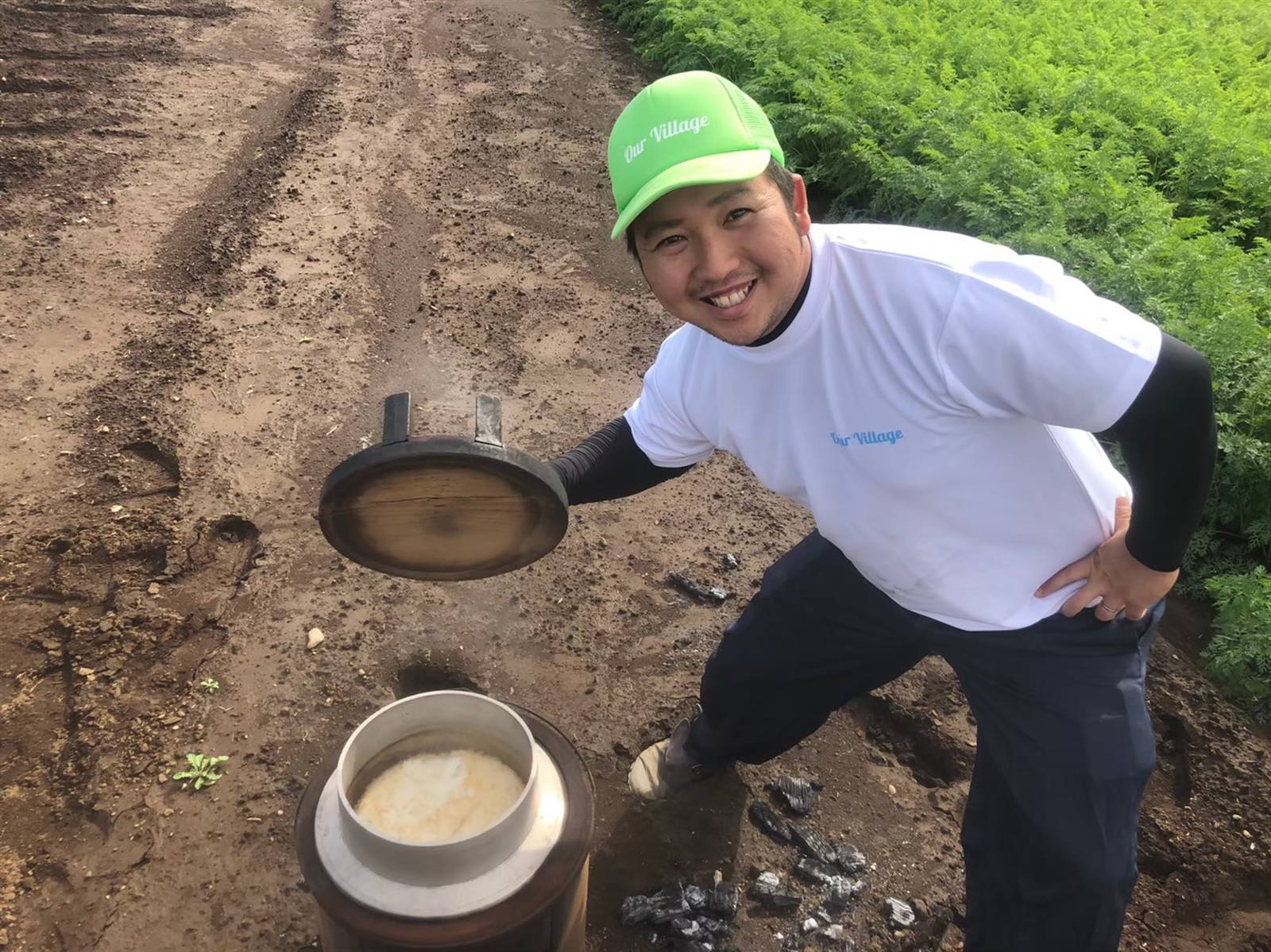 畑で炊きたての羽釜ご飯を見せるスタッフ